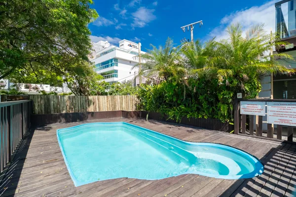 Piscina com deck de madeira e vegetação
